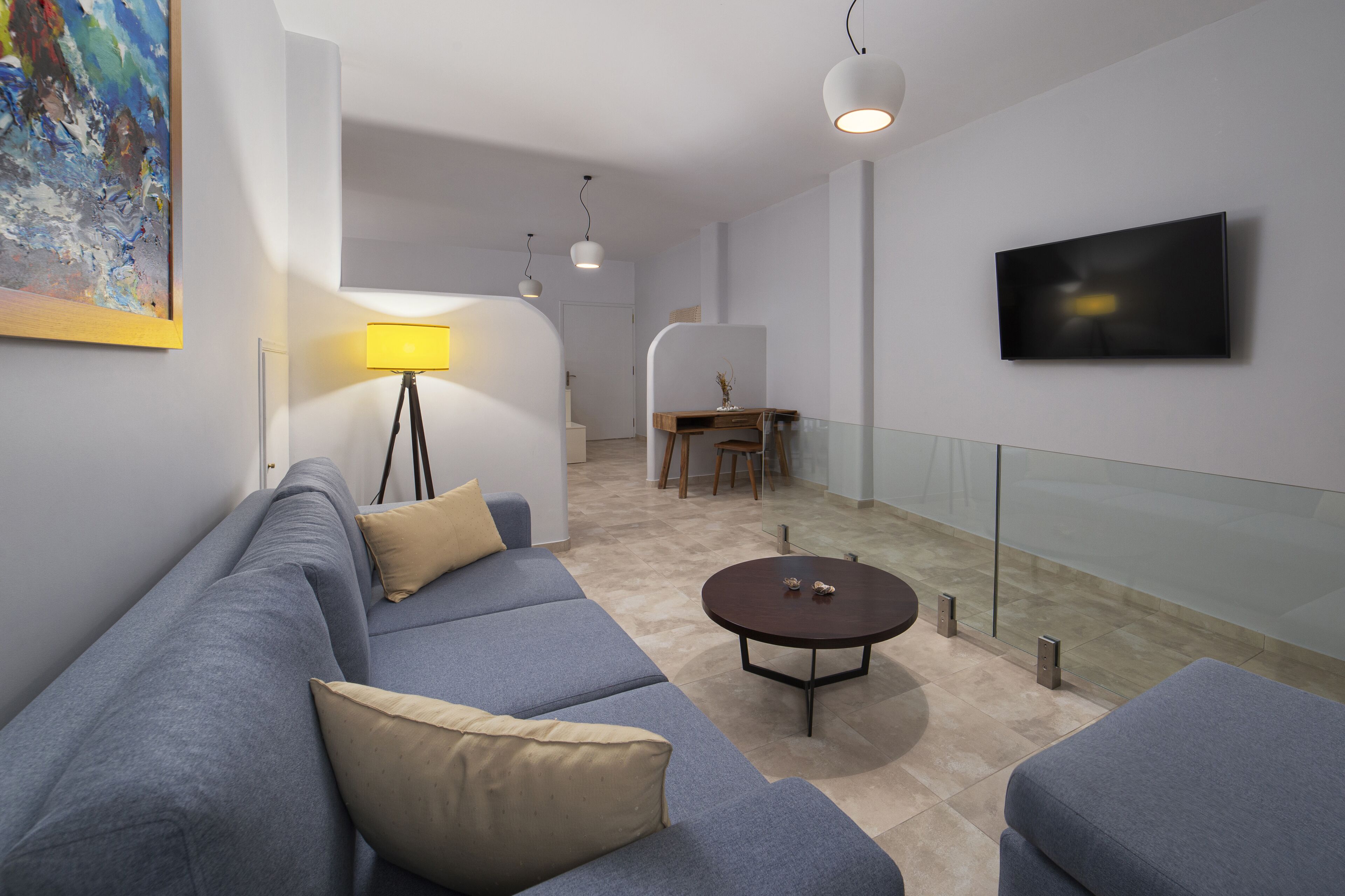 A modern living room with a sofa, a coffee table, and a TV mounted on the wall.