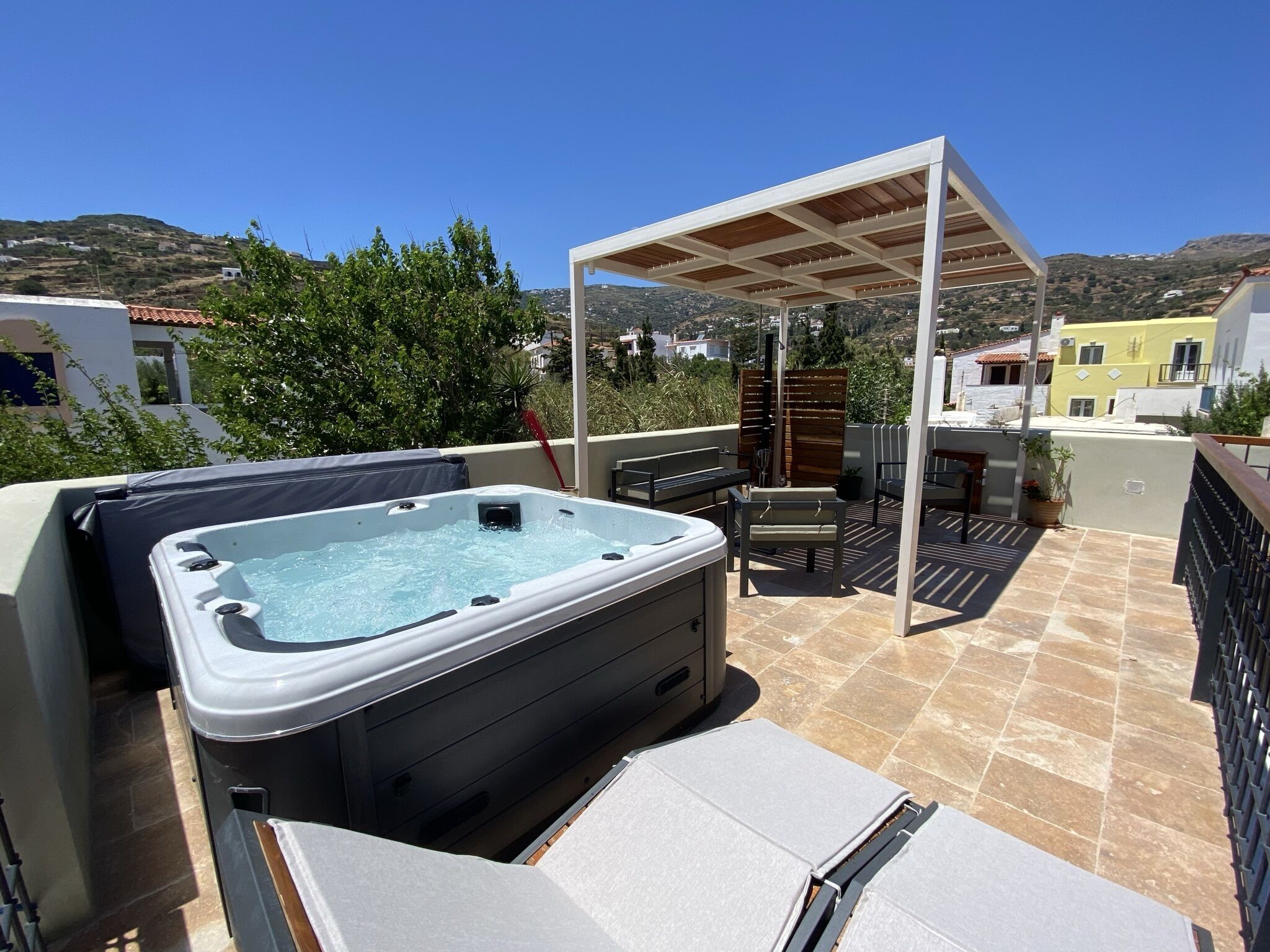 Une terrasse sur le toit avec un jacuzzi, du mobilier d’extérieur et une pergola.