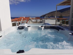 A hot tub with a view of the sea and buildings in the background. - Andros 4 All Seasons Villas & Suites (Andros)
