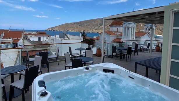 Une terrasse sur le toit avec un jacuzzi, des sièges extérieurs et une vue sur la mer et les collines.
