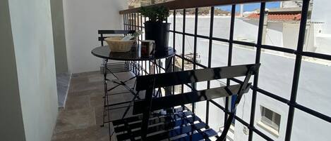 A balcony with a table, chairs, and a potted plant.