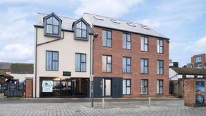 A two-story building with a beige facade and a brick section. - Elliot Oliver - Loft Style 2 Bedroom Apartment With Parking In The Docks (Gloucester)