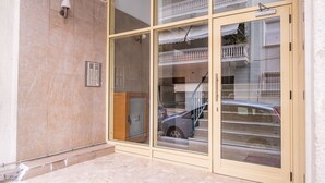 Un ingresso di un edificio con una grande porta in vetro, una piccola finestra e un fiorino sulla parete.