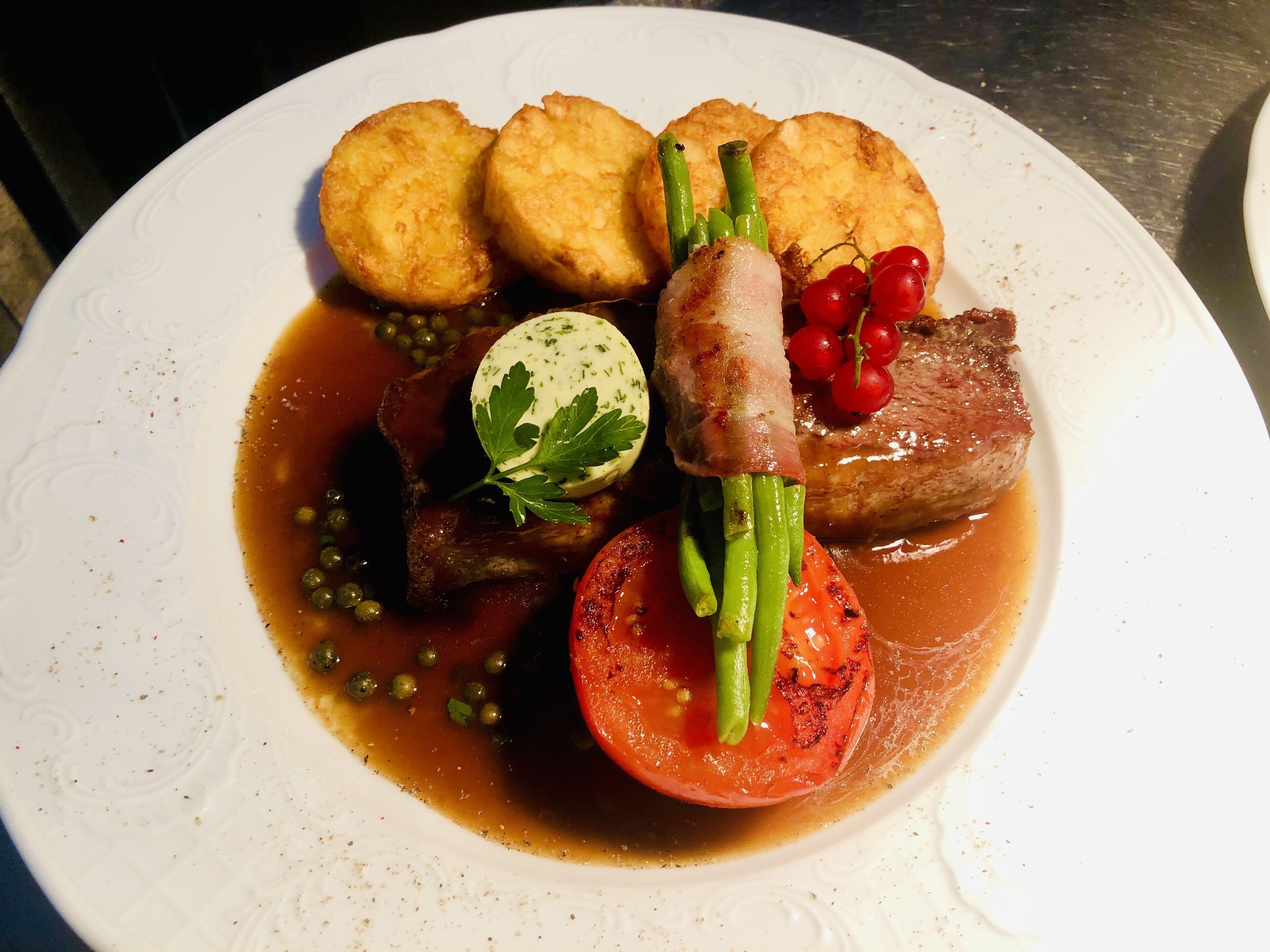 Un plato de comida con diversos ingredientes, incluyendo carne, verduras y un huevo cocido.