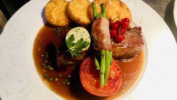 Un plato de comida con diversos ingredientes, incluyendo carne, verduras y un huevo cocido.