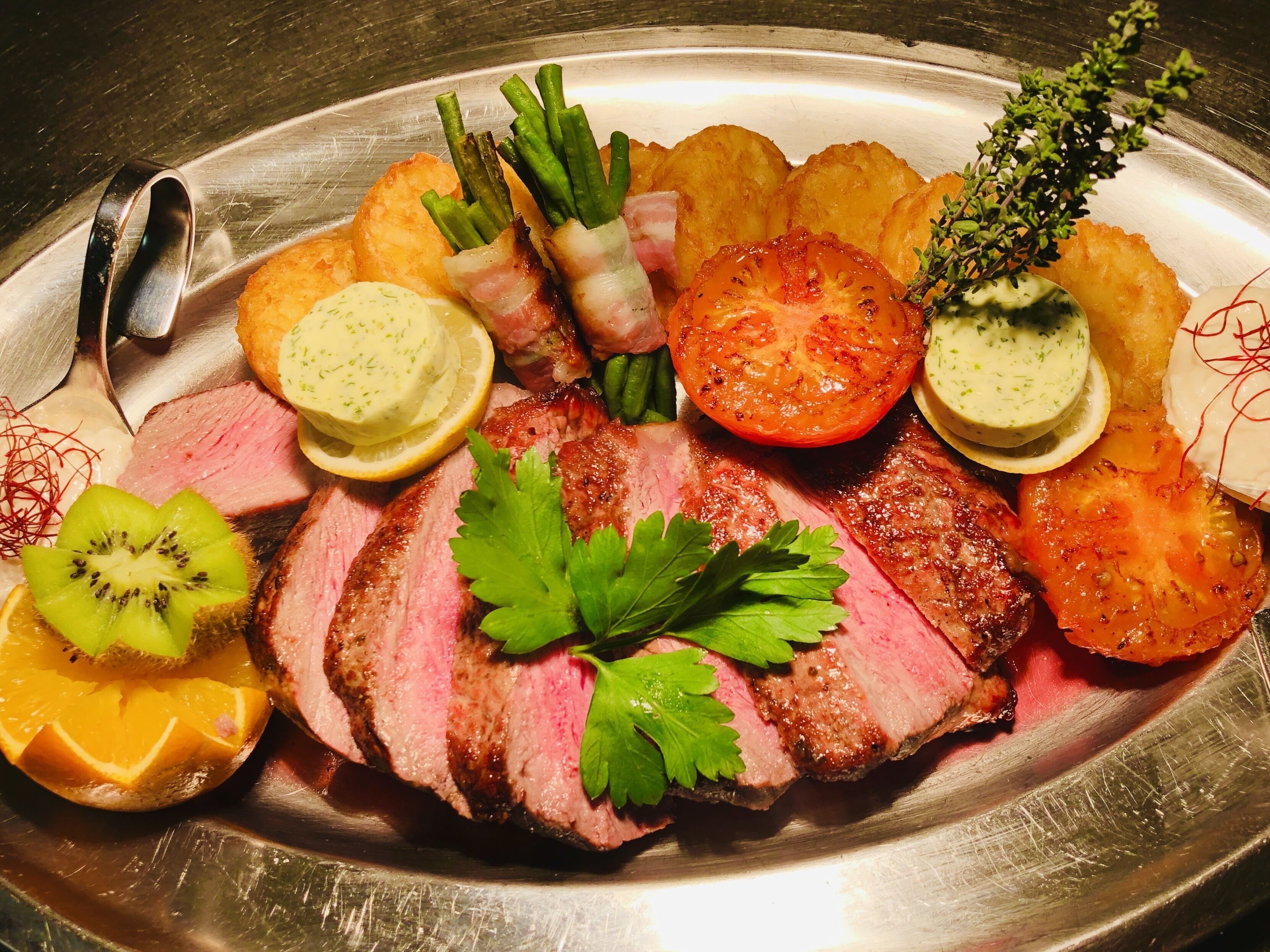 Un plato con carne en rodajas, verduras y salsas.