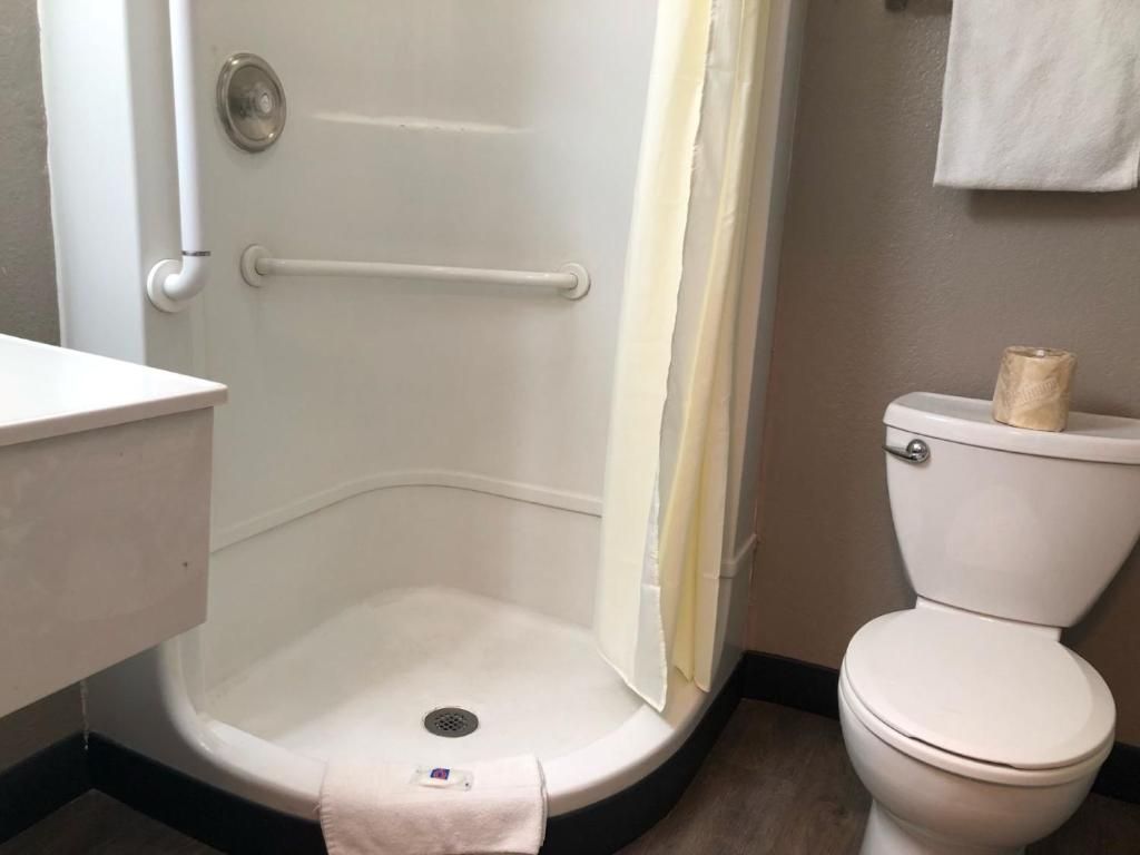 A bathroom with a white toilet, a shower with a white door, and a towel rack.