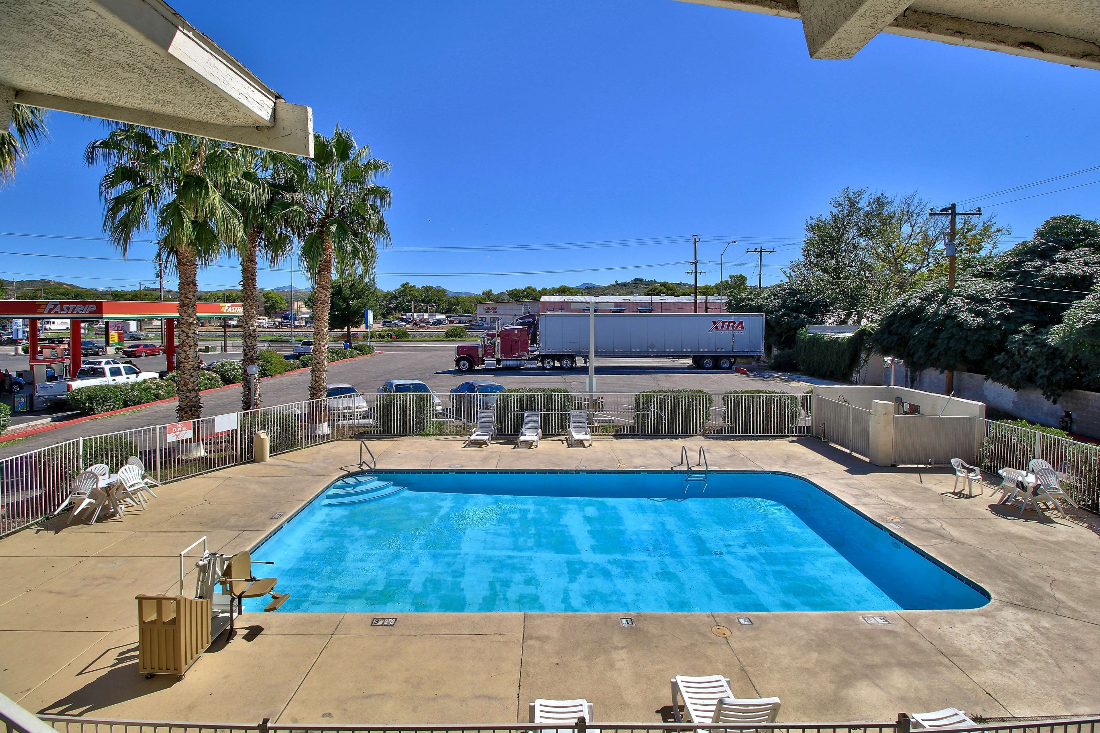 Une piscine avec des chaises longues, des palmiers et une station-service en arrière-plan.