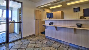 A reception area with a glass door, a counter with a phone, a TV, and a computer.