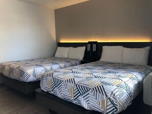 Two beds with patterned bedding, a dark headboard, and a wall-mounted light. - Motel 6 Nogales, AZ - Mariposa Road (Nogales)