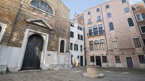 A courtyard with a fountain, surrounded by historic buildings with arched windows and a prominent brick facade.
