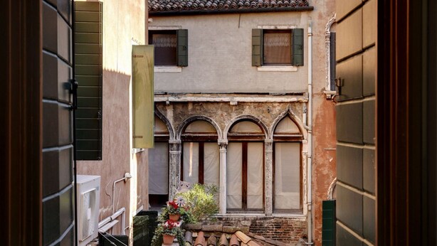 A narrow alleyway with a building featuring arched windows and a tiled roof.
