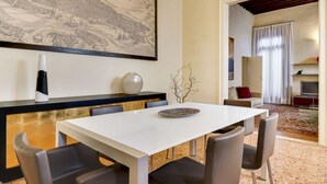 A dining area with a white table and chairs, a large black-and-white map on the wall, and a modern kitchen in the background.