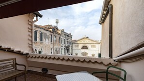 A balcony with a table and chairs, overlooking historic buildings with classic architecture. - CA' SVEVA VENICE APARTMENT M0270429660 (Venezia)