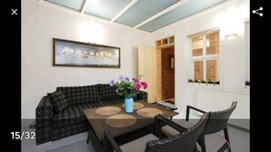 A living room with a patterned sofa, a dining table with placemats, a vase with flowers, and a framed picture on the wall. - Newly renovated apartment- studio (Balat Fatih)