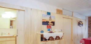 A room with a wooden wall, a sink, a mirror, a small table with a vase, and a poster of a tower. - Newly renovated apartment- studio (Balat Fatih)