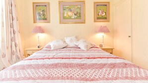 A bedroom with a bed, two bedside tables, and three framed pictures on the wall. - Smart flat near Pimlico Tube (London)