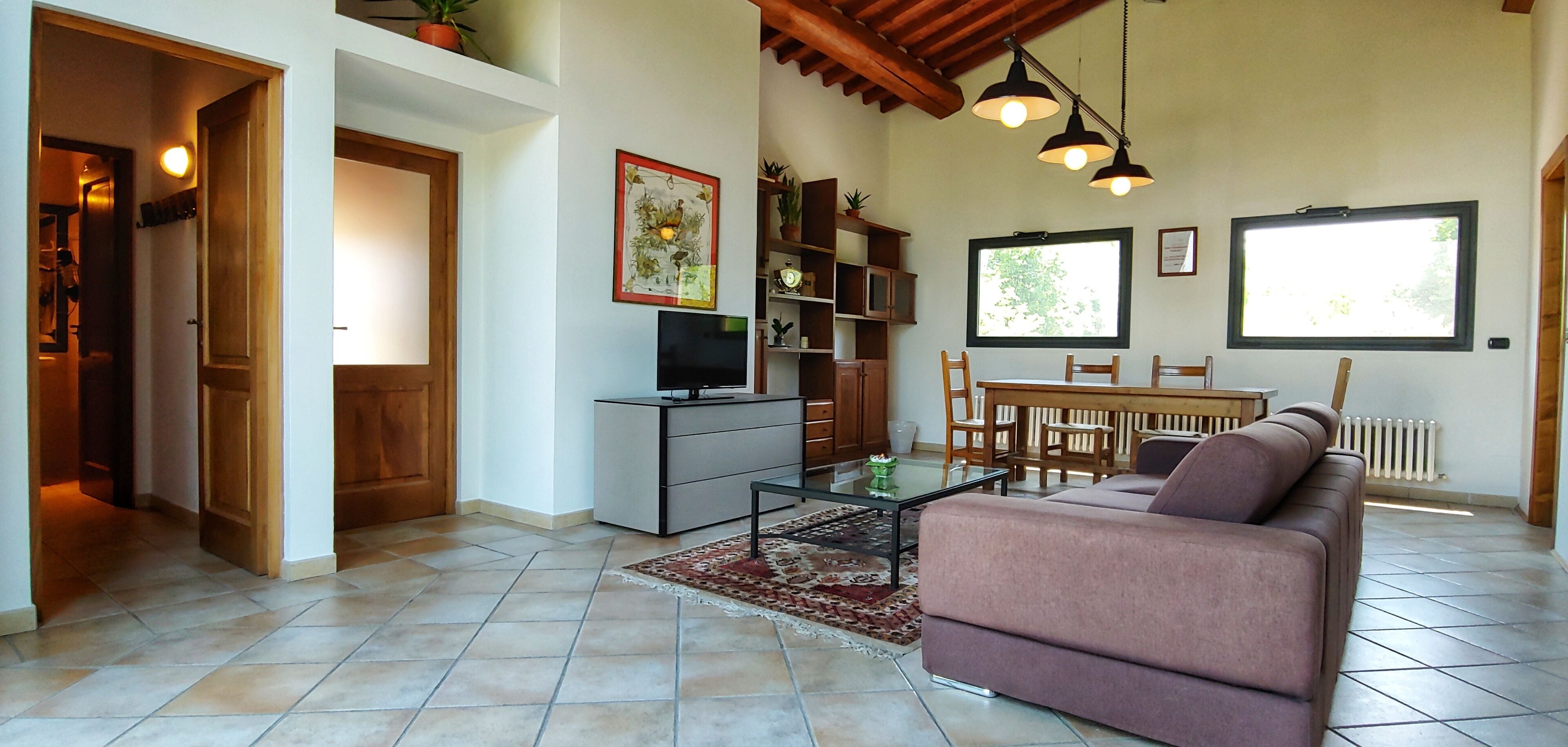 Un salon comprenant un canapé, un téléviseur et un coin repas avec des chaises et une table.