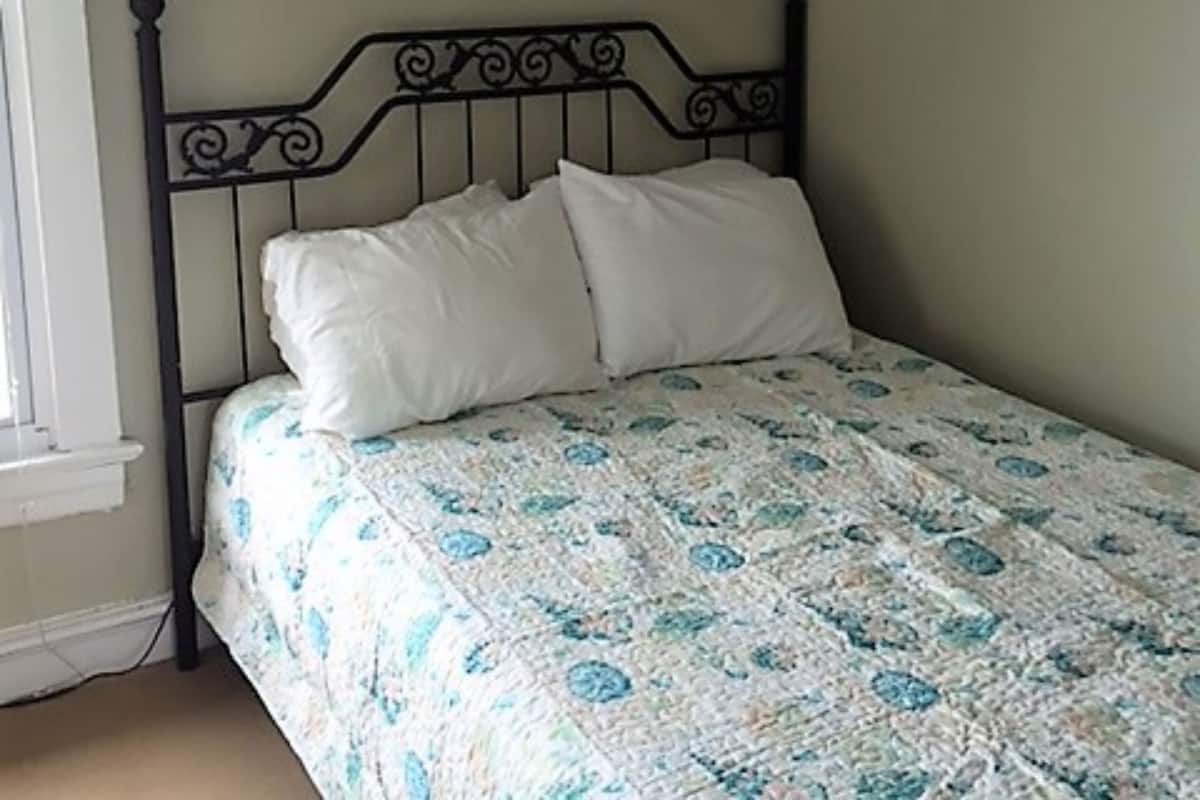 Un dormitorio con una cama, una ventana y dos cuadros en la pared.