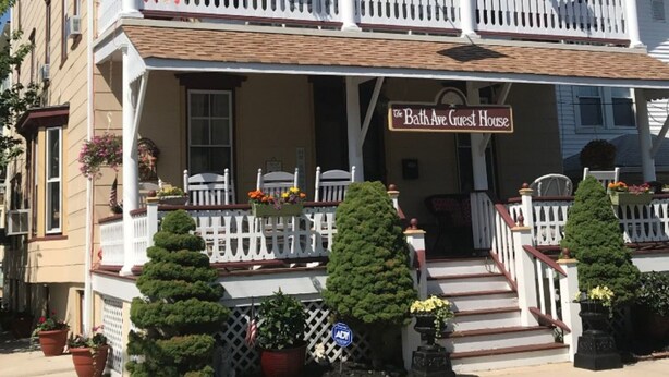 A two-story building with a balcony and a sign reading "The Bath Ave Guest House". - Bath Avenue House (Ocean Grove)