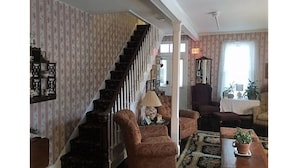 A staircase leading to an upper floor, a seating area with a table and chairs, and a window with curtains. - Bath Avenue House (Ocean Grove)