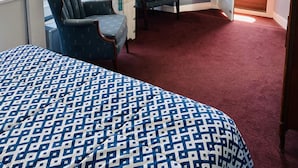 A bedroom with a bed, two armchairs, a small table, a painting, and a door leading to a balcony. - Bath Avenue House (Ocean Grove)