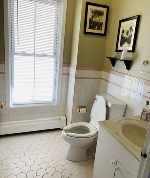 A bathroom with a toilet, sink, and window with blinds. - Bath Avenue House (Ocean Grove)