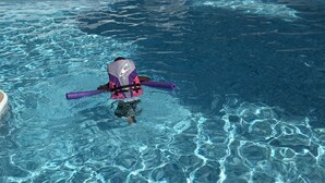 Una piscina cristalina con un niño usando una tabla de patadas.