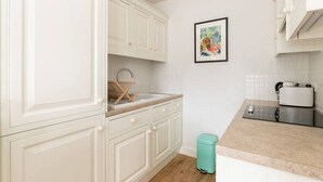 Een keuken met witte kastjes, een spoelbak, een broodrooster en een prullenbak.