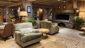 A cozy lobby with a stone fireplace, plush seating, and a Christmas tree. - Skiing and après ski in pain and residence (Les menuires)