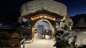 A snow-covered entrance with a wooden archway and a view of snow-covered mountains in the background. - Skiing and après ski in pain and residence (Les menuires)
