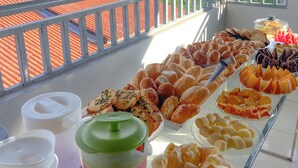 A balcony with a variety of baked goods and beverages, overlooking a river and greenery. - Canto da Duna Hotel (Barreirinhas)