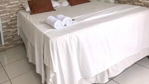 A hotel room with a bed, white curtains, a painting on the wall, and a tiled floor. - Canto da Duna Hotel (Barreirinhas)
