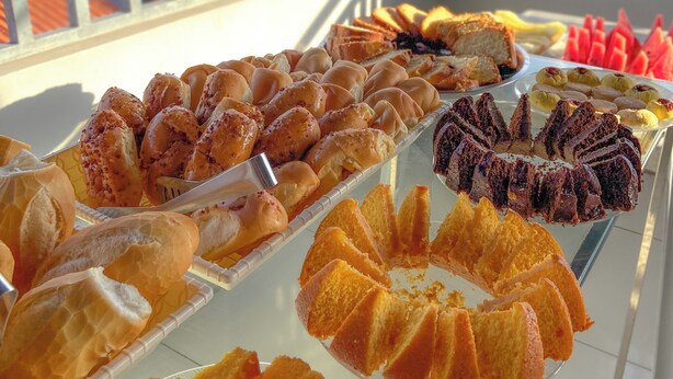 A buffet table with various baked goods and desserts on a balcony with a view of the countryside. - Canto da Duna Hotel (Barreirinhas)