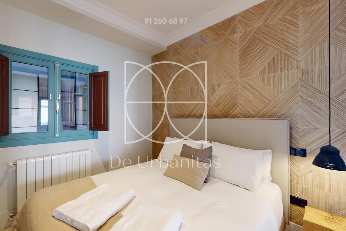 Quarto moderno com cama, janela com persianas de madeira, radiador e papel de parede estampado.