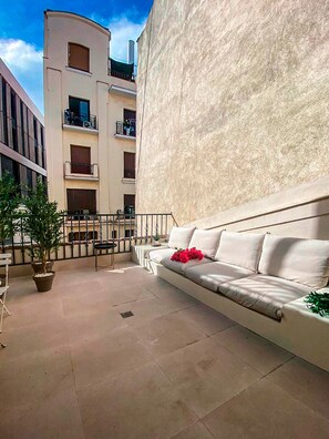 A modern outdoor seating area with a sofa and chairs, surrounded by potted plants. - Sol y El Madroño (Madrid)