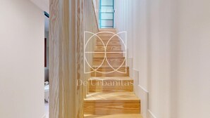 Eine moderne Treppe mit Holzstufen und einem Glasgeländer, die zu einem Raum mit weißen Wänden führt.