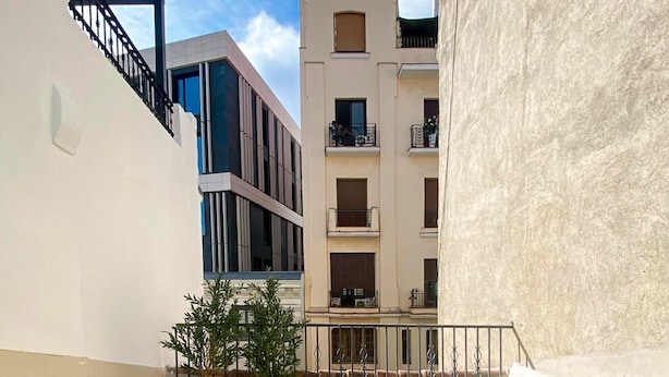 Ein Außenbereich mit einer Terrasse, einem weißen Sofa, weißen Stühlen und Topfpflanzen.