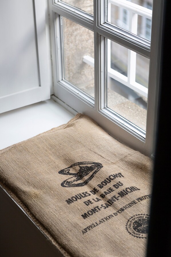 A window with a white frame and a burlap bag with text and a logo on a windowsill.