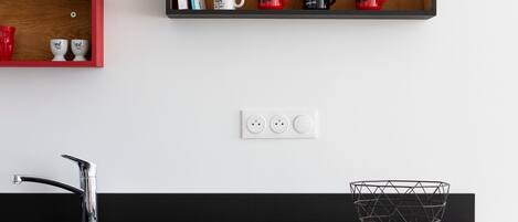 Una cocina moderna con encimera de madera, un lavamanos negro y una zona de comedor con una mesa dispuesta para dos.