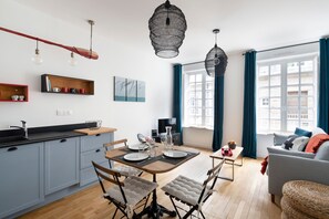A modern kitchen with a dining area, wooden flooring, and a view of the city through large windows.