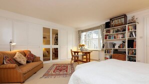 A cozy bedroom with a large bed, a sofa, a desk, and a bookshelf. - Unique flat near Crescent Garden (London)