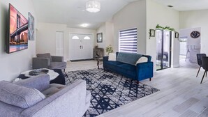 A modern living room with a blue sofa, grey armchairs, and a patterned rug. - Fabulous 3/2 Home in Ft Lauderdale suburb. (Lauderhill)