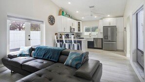 A modern kitchen with white cabinets, a stainless steel refrigerator, and a dining area with white chairs. - Fabulous 3/2 Home in Ft Lauderdale suburb. (Lauderhill)