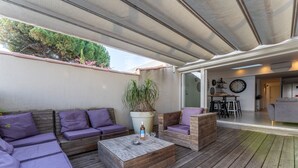 An outdoor patio area with wooden flooring, a wooden coffee table, and purple cushioned seating. - VILLA HESTIA - Vue sur la Marina (Agde)