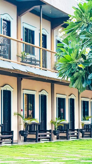 A building with multiple balconies, outdoor seating, and a well-maintained lawn. - La Plumerias (Moalboal)