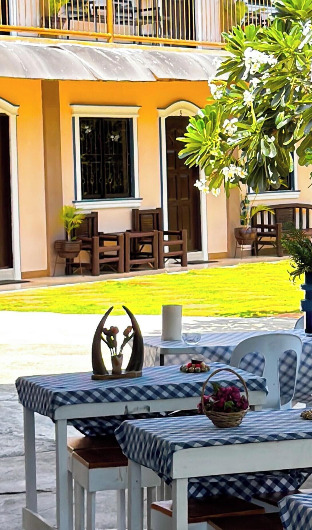 A patio area with a checkered tablecloth, chairs, and a decorative centerpiece.