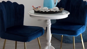 A room with a round white table, two blue velvet chairs with gold legs, a blue ceramic coffee pot, and a tray with decorative items. - Soggiorno La Coccinella (Florence)