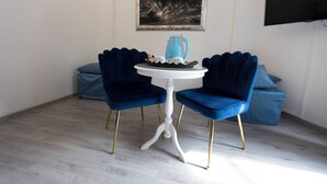 A room with a white table and two blue chairs, a blue coffee pot on the table, and a painting on the wall. - Soggiorno La Coccinella (Florence)