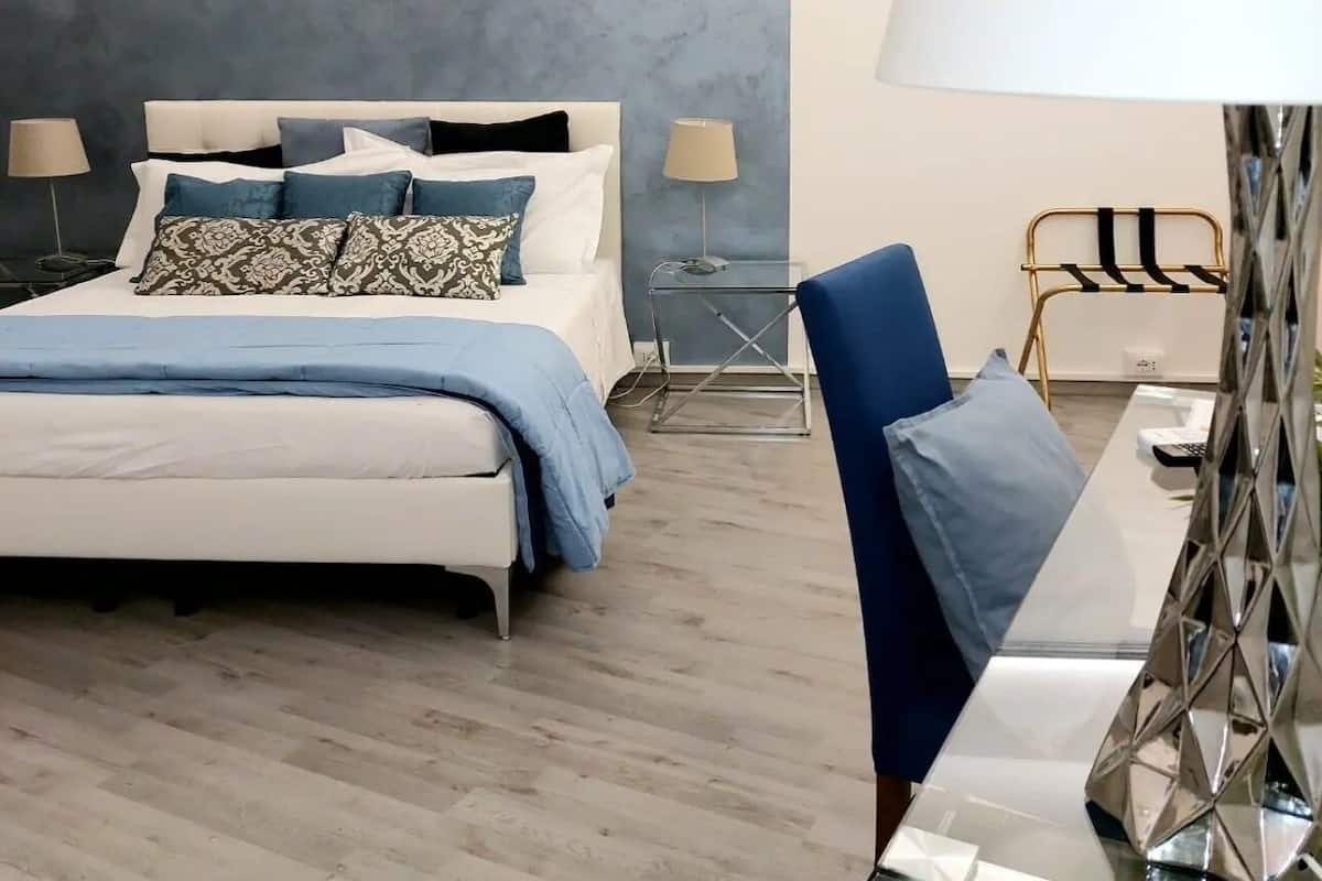 Ein modernes Schlafzimmer mit einem Bett, Nachttischen, einem Sessel und einer Lampe.